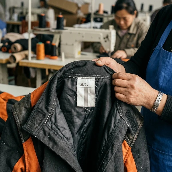 Woven size label sewn inside the collar of a fleet kart suit